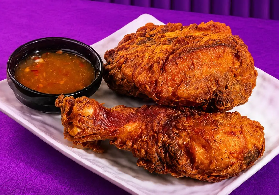 Dark, crisp Bangkok fried chicken with a bowl of dipping sauce.