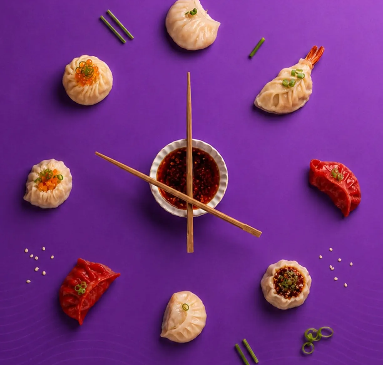 Dumplings arranged like a clock face around a bowl of chili oil, with chopsticks as the hands.