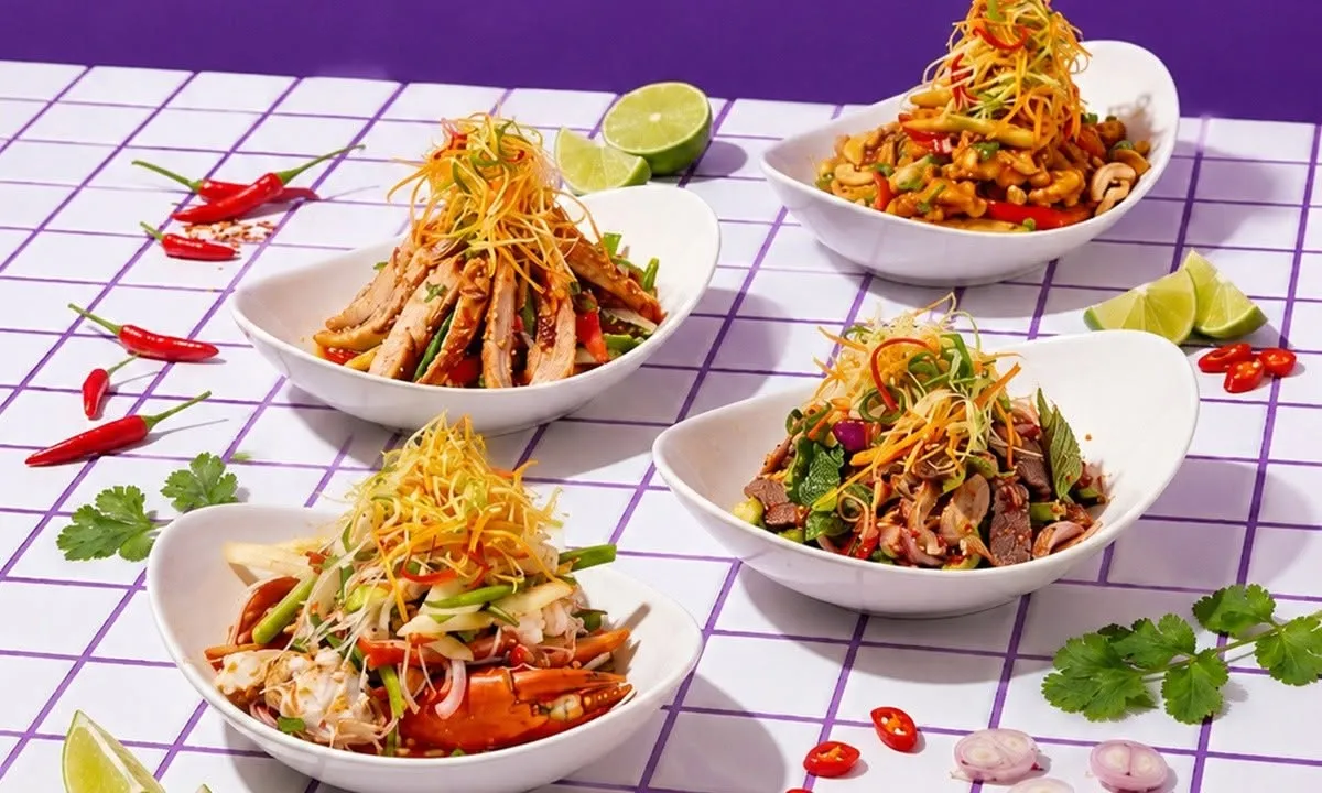 Four Thai style salads in white bowls on a tiled table.