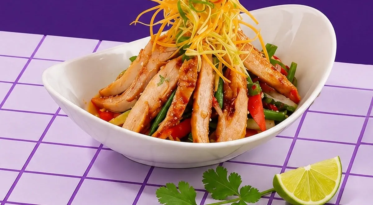 Thai style grilled chicken salad in a white bowl with lime.