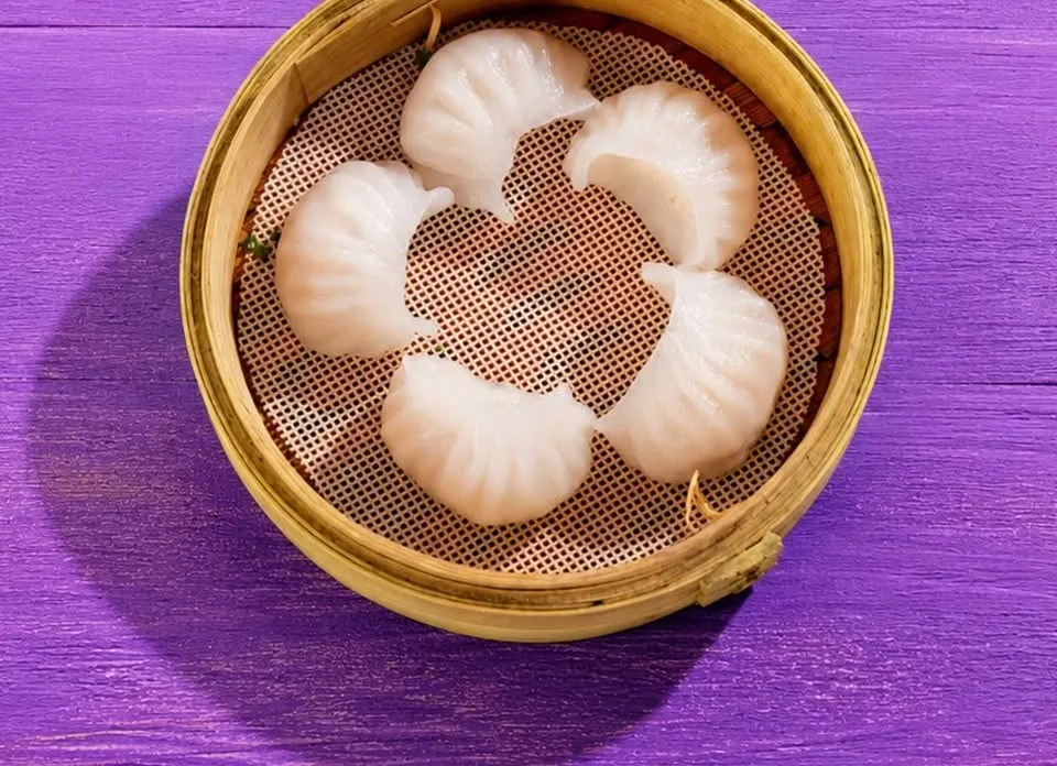 Five prawn har gow in a bamboo steamer, seen from above.