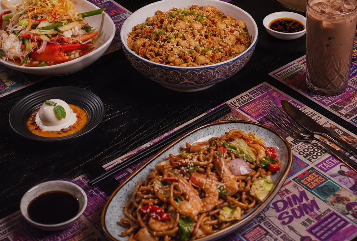 A table set with noodles, fried rice, salad and iced drinks.