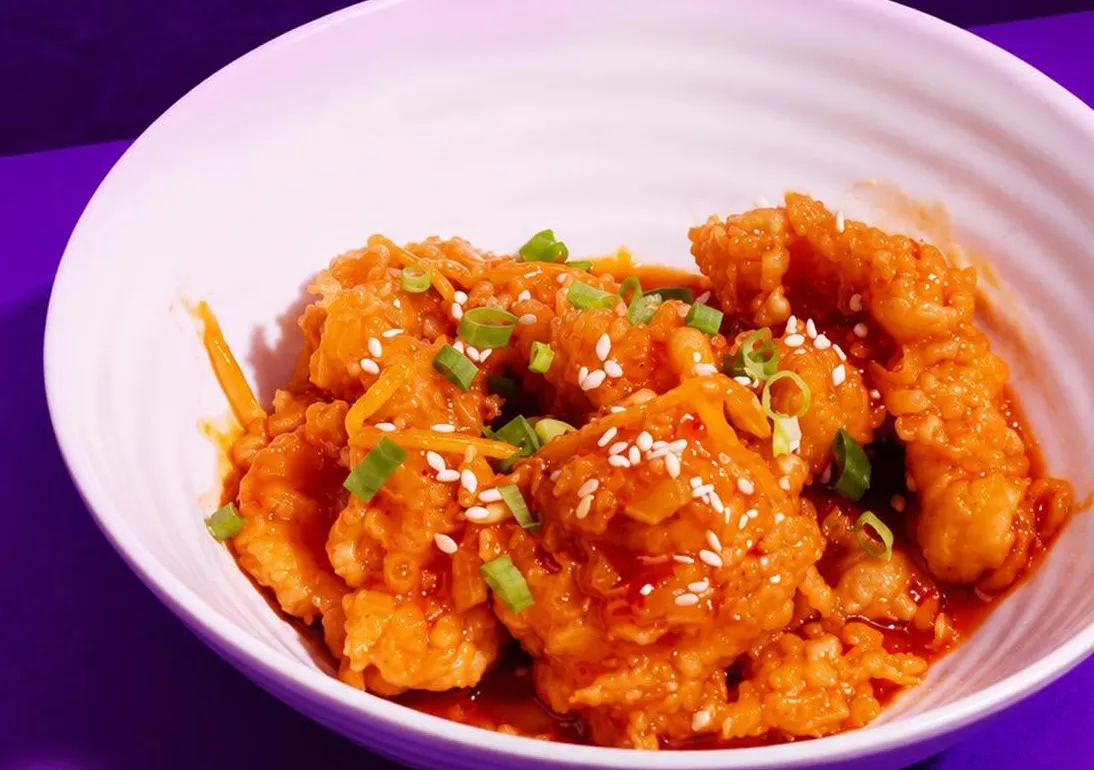 Tangerine chicken with sesame in a white bowl.
