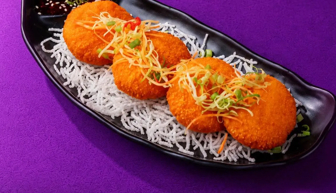 Three golden shrimp cakes on crispy noodles.